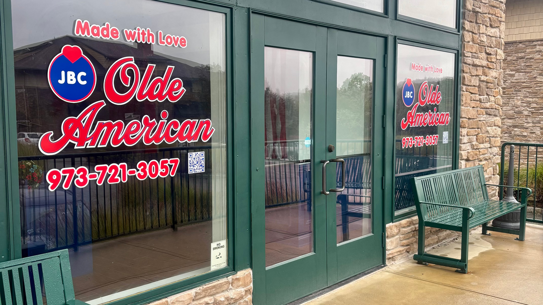 Storefront with 'Olde American' branding and contact information on glass doors and windows.